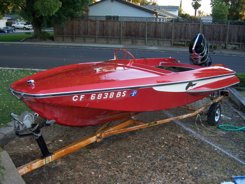 red boat with white stripe and dolphin graphic on trailer
