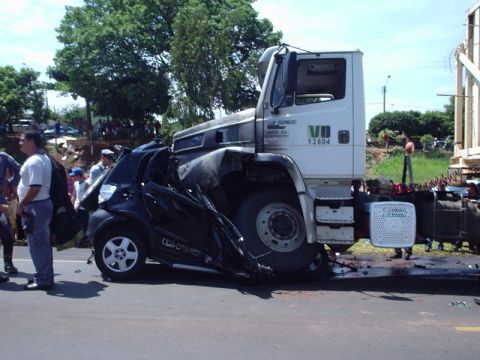 1987 Ford Thunderbird - A black car is severely damaged after being run over by a large white truck.