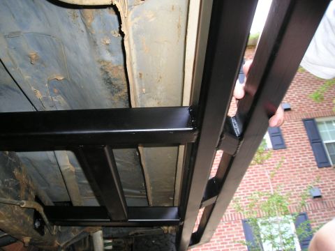 1989 Ford Bronco - Aftermarket rock sliders are mounted to the undercarriage of a vehicle, with a brick house visible in the background.