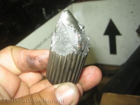 1987 Suzuki Samurai - A close-up shows a fractured metal axle part with visible splines, held by a hand with dirty fingers.