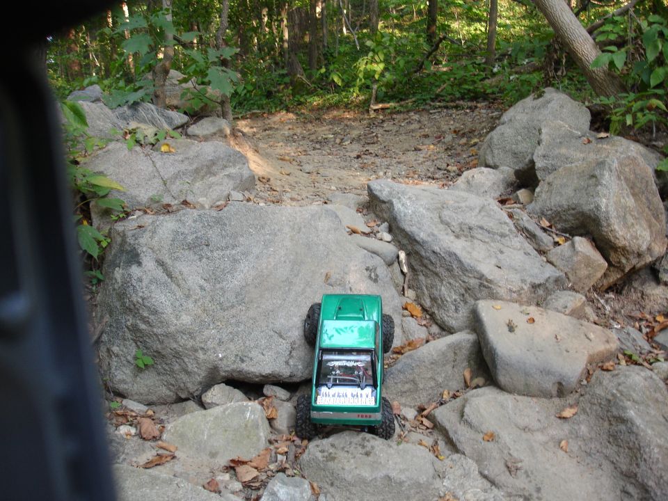 Green RC rock crawler on a rocky trail in the woods