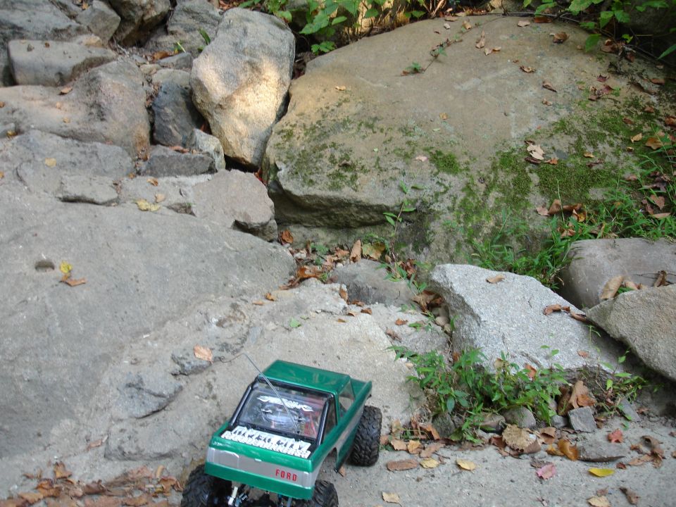 Green toy truck with "FORD" text on grille, parked on rocky terrain