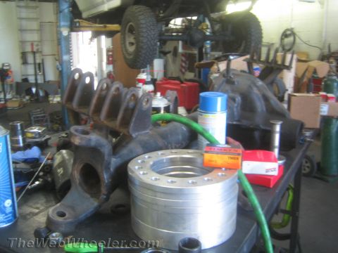 1968 Ford Mustang - Various automotive parts, including spacers and differential components, are laid out on a workbench in a workshop setting.