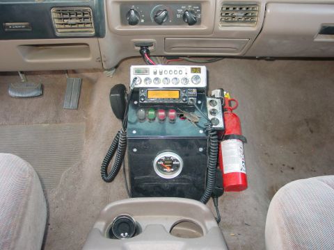 1994 Ford Bronco - Custom console setup in a vehicle includes a CB radio, fire extinguisher, and various switches and gauges.