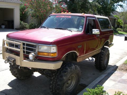 1995 Ford Bronco - This red 1995 Ford Bronco features a lifted suspension and an aggressive aftermarket bumper.