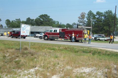 1998 Ford Crown Victoria - Emergency vehicles and other vehicles are stopped on the side of the road near a business.