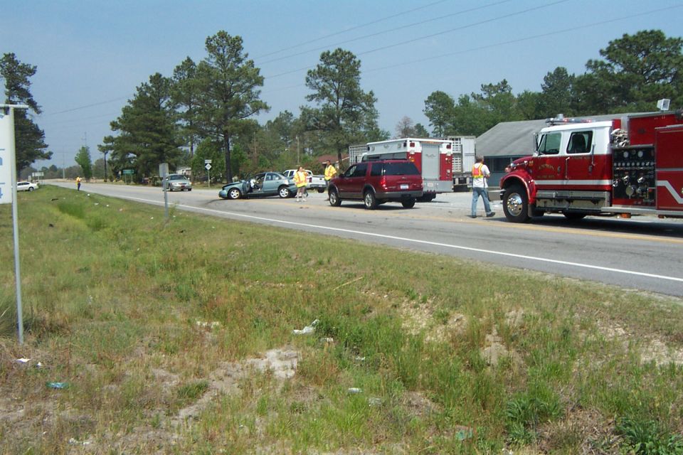 Car accident scene with a blue sedan, red SUV, and fire truck on a two-lane road