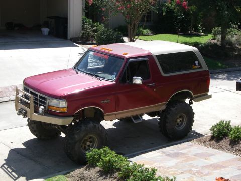 1995 Ford Bronco - This lifted 1995 Ford Bronco is parked in a suburban driveway with a garage in the background.