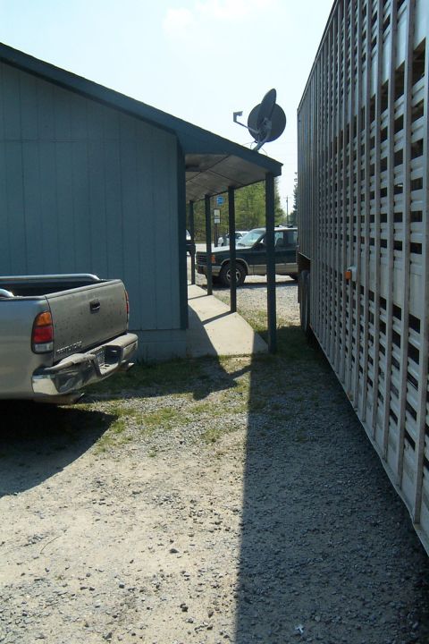 1998 Ford Crown Victoria - A pickup truck and livestock trailer are parked next to a building on a sunny day.