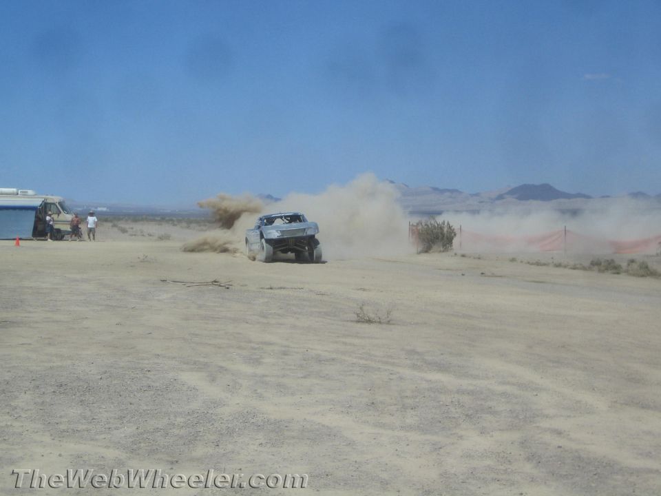 Off-road race truck kicking up a wall of dust in the desert