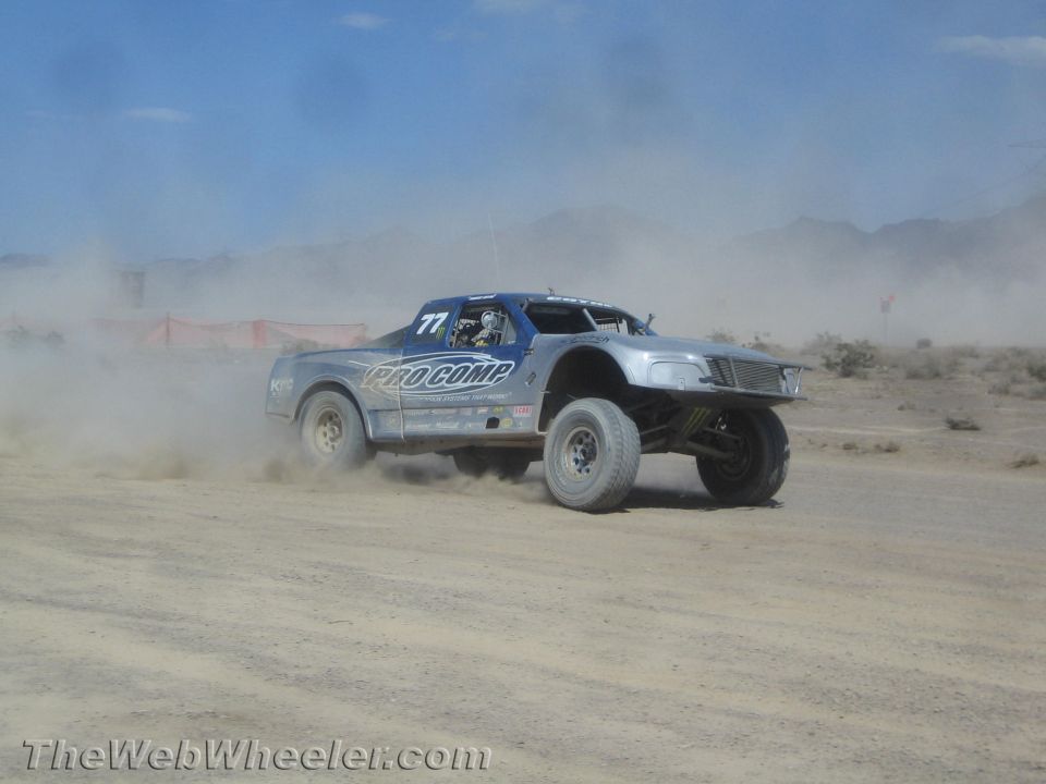 Silver Pro Comp off-road race truck number 77 racing in the desert