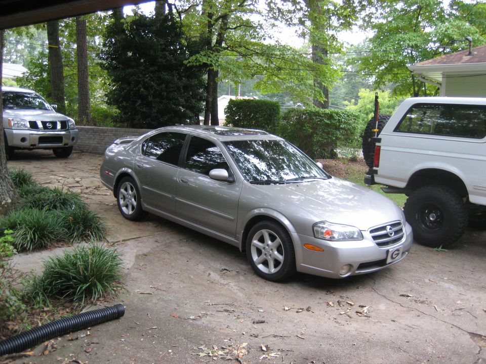 Silver Nissan Maxima sedan front three-quarter view on stone driveway