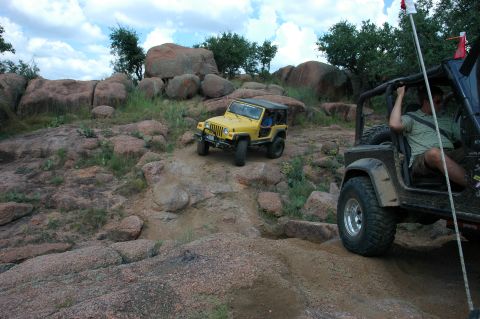 2001 Jeep Wrangler - Two Jeeps navigate a challenging rocky off-road course under a cloudy sky.