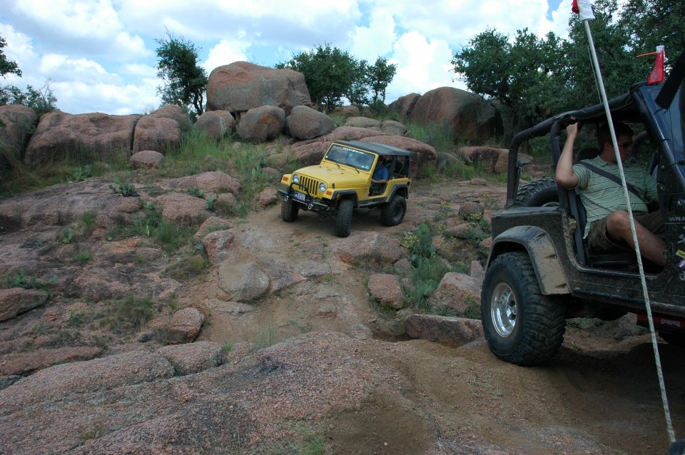 Yellow Jeep Wrangler climbing a rocky hill with another Jeep to its right