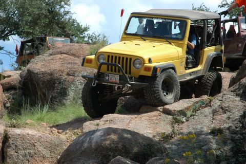 2001 Jeep Wrangler - A yellow 2001 Jeep Wrangler tackles a rocky trail, with another Jeep visible in the background.