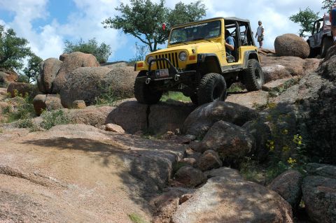 2001 Jeep Wrangler - Yellow 2001 Jeep Wrangler navigating a rocky trail with another vehicle in the background.