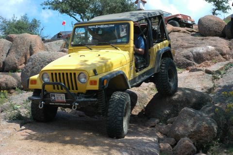 2001 Jeep Wrangler - A yellow 2001 Jeep Wrangler navigates a rocky trail, with another Jeep visible in the background.