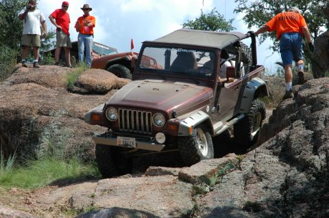 2001 Jeep Wrangler - A brown 2001 Jeep Wrangler navigates a rocky trail while onlookers observe the off-road adventure.