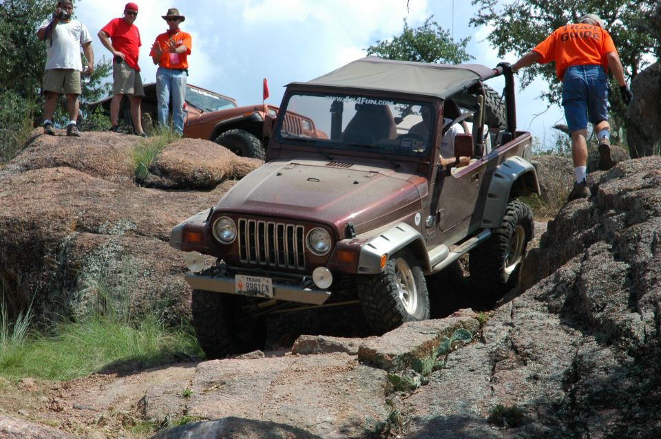 Brown 2001 Jeep Wrangler off-roading on rocks with people watching