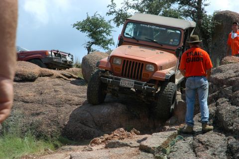 2001 Jeep Wrangler - Two Jeeps navigate a rocky off-road trail with a guide observing.