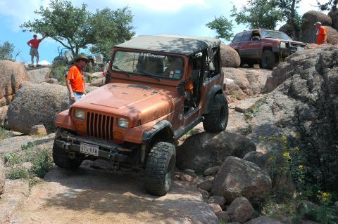 2001 Jeep Wrangler - Two Jeeps off-road on a rocky trail with people watching.