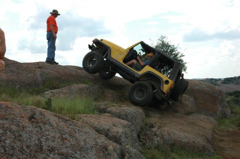 2001 Jeep Wrangler - A yellow 2001 Jeep Wrangler navigates a rocky incline, demonstrating its off-road capabilities.