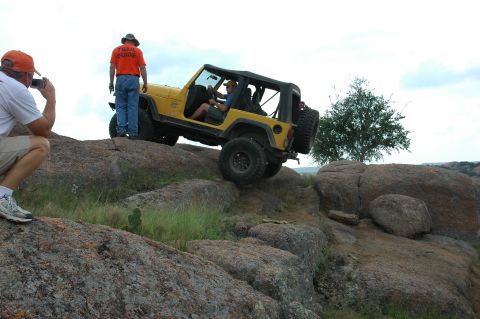 2001 Jeep Wrangler - A yellow Jeep Wrangler navigates a rocky trail with a trail guide and photographer present.