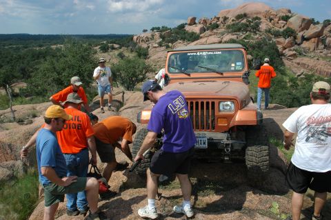 2001 Jeep Wrangler - Group of people gathered around an orange Jeep Wrangler in a rocky, outdoor landscape.