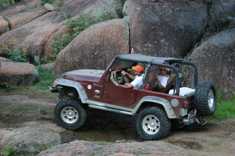 2001 Jeep Wrangler - A maroon 2001 Jeep Wrangler navigates a rocky trail with two people inside.