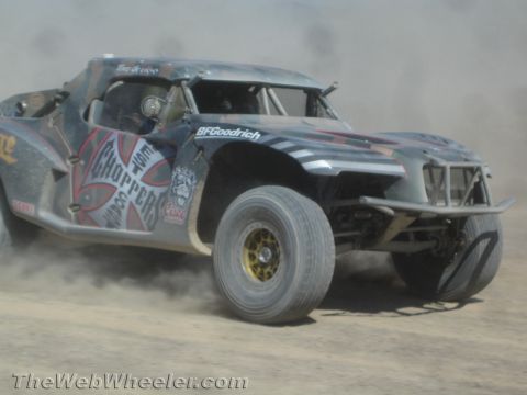 1990 Ford Bronco - black off-road race truck with West Coast Choppers graphics and BFGoodrich tires powers through the desert.