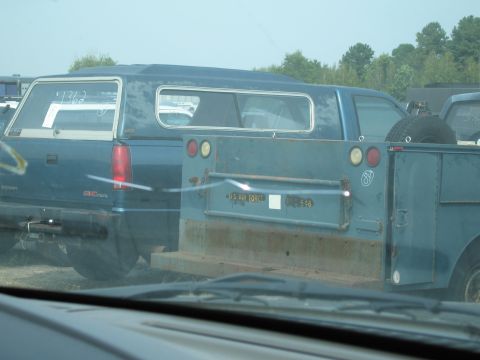 1991 Ford LTD Crown Victoria - A blue pickup truck with a camper shell is parked next to a utility trailer that has 'US AIR FORCE' markings.