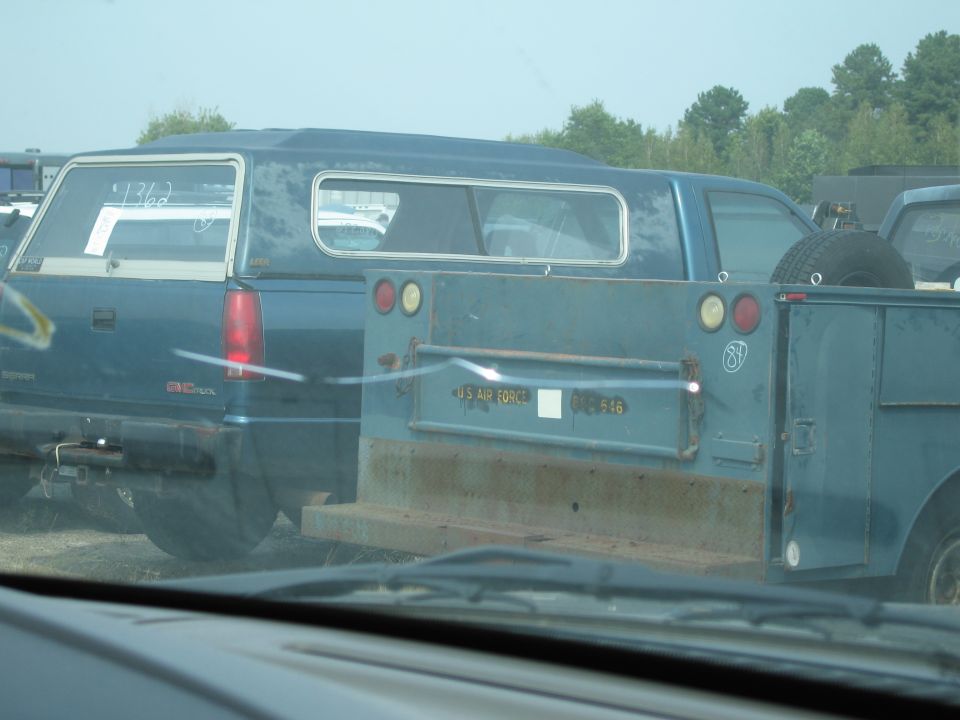 Blue pickup truck with camper shell and utility trailer, 'US AIR FORCE' text visible