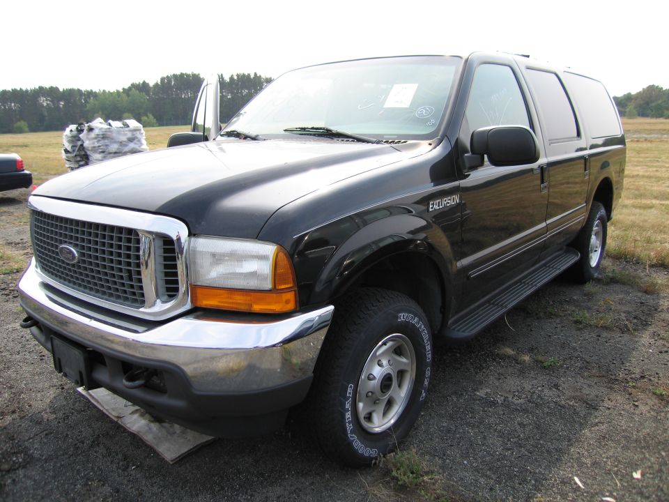Black Ford Excursion SUV with running boards, chrome grille, and an open driver's door