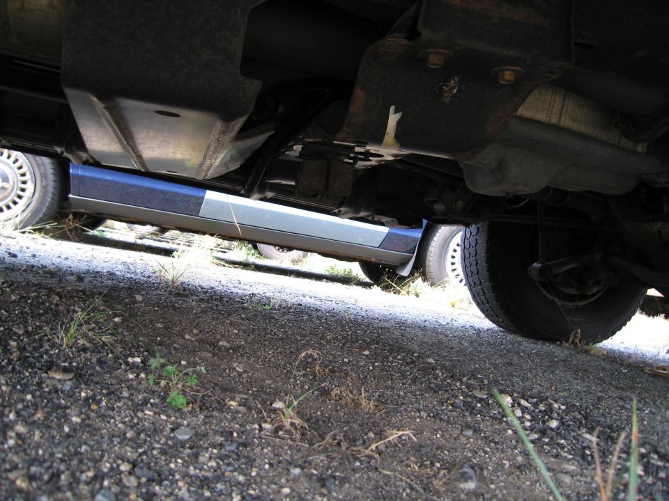 Underside view of a car showing the frame, exhaust, and tires