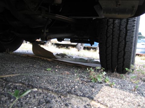1991 Ford LTD Crown Victoria - A low-angle shot shows the undercarriage of a vehicle, with other cars parked nearby.