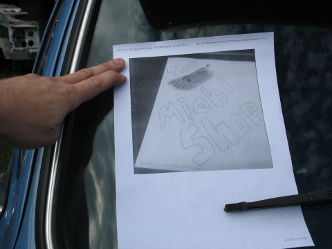1978 Ford Bronco - A document displaying a drawing of a shoe with the text 'The Miobi Shoe' is held up against a vehicle's windshield.