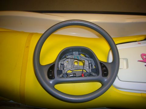 2000 Ford Crown Victoria - A steering wheel is shown, detached from a vehicle, against a bright yellow background.