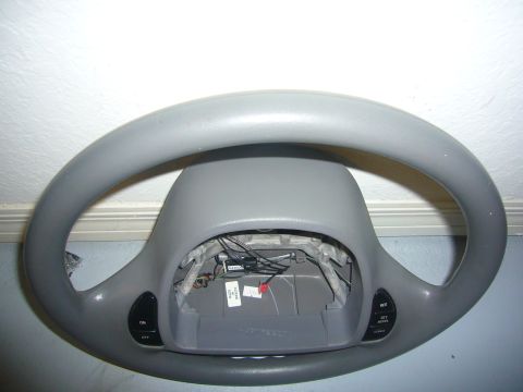 2000 Ford Crown Victoria - A gray steering wheel with visible wiring and control buttons is shown, detached from a vehicle.