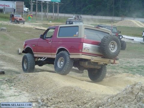 1995 Ford Bronco - This lifted Ford Bronco is navigating an off-road course with other vehicles present.