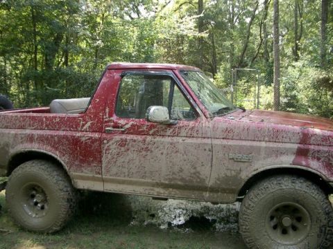 1995 Ford Bronco - This red 1995 Ford Bronco is heavily covered in mud after off-roading.