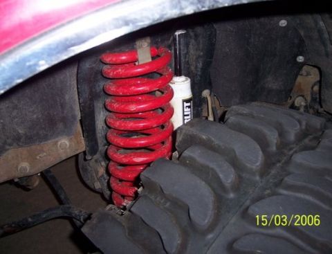 1995 Ford Bronco - Close-up of suspension components including a red coil spring and a shock absorber.