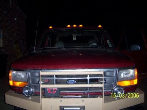 1995 Ford Bronco - A red Ford pickup truck is shown at night, a prominent brush guard and auxiliary lighting.