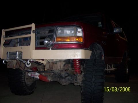 1995 Ford Bronco - Front view of a red Ford Bronco modified with a brush guard and winch, showing off its suspension components.