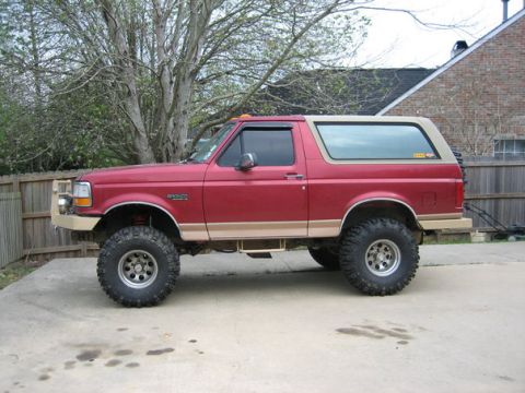 1995 Ford Bronco - This lifted Ford Bronco displays a two-tone paint scheme and aftermarket wheels, suggesting a model year in the early to mid-1990s.