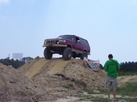 1995 Ford Bronco - Red 1995 Ford Bronco navigates an off-road obstacle course on a dirt hill.
