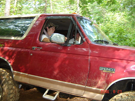 1995 Ford Bronco - A red Ford Bronco is driven through a wooded area, kicking up dirt.