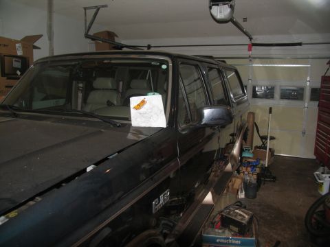 1978 Ford Bronco - A dark SUV sits in a garage, with a paper placed on its dashboard.