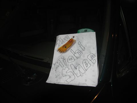 1978 Ford Bronco - A drawing of a shoe labeled 'the Miobi Shoe' rests on the hood of a dark-colored vehicle.