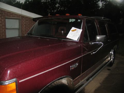 1978 Ford Bronco - A maroon SUV is parked outside a building, with a paper visible on its dashboard.