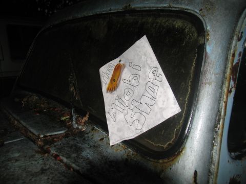 1978 Ford Bronco - A piece of paper with a drawing of a foot and the words 'the Miobi Shoe' is placed on the dirty windshield of a weathered vehicle.